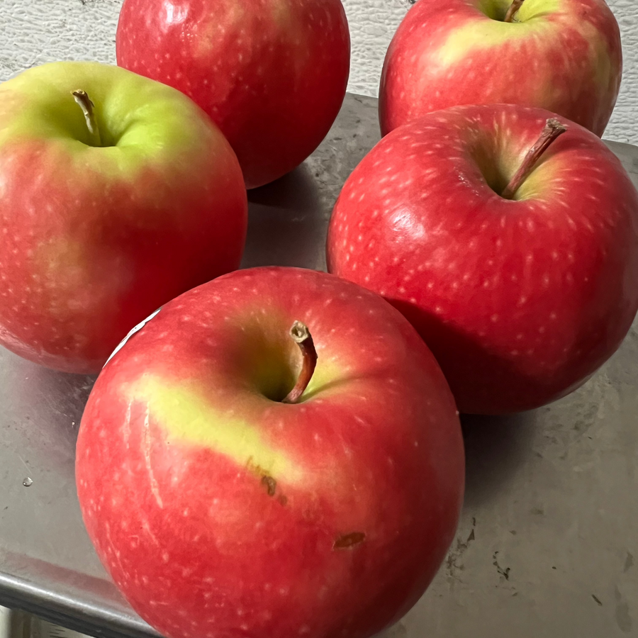 Three Fuji apples on a concrete surface