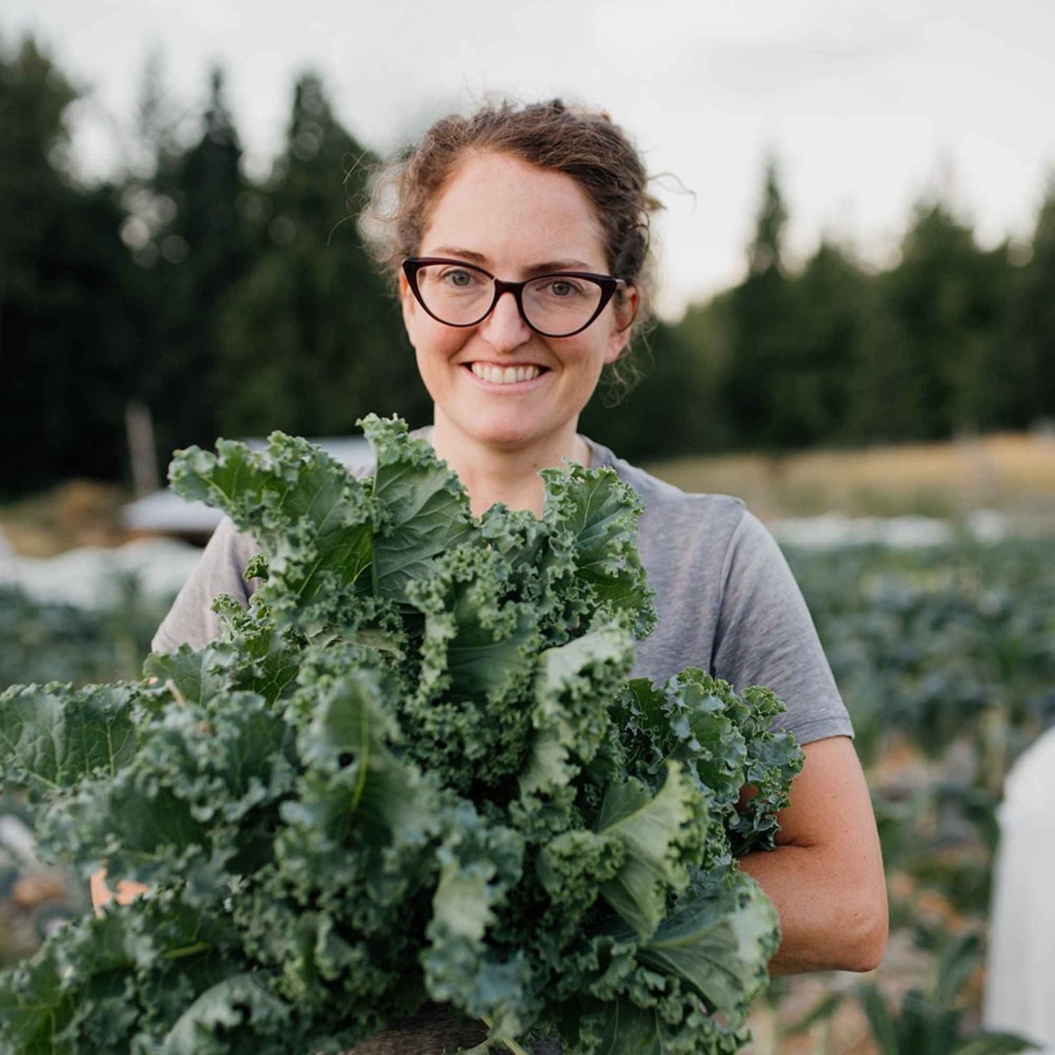 Emily Jubenvill holding a large bunch of fresh kale at Shuswap Organics