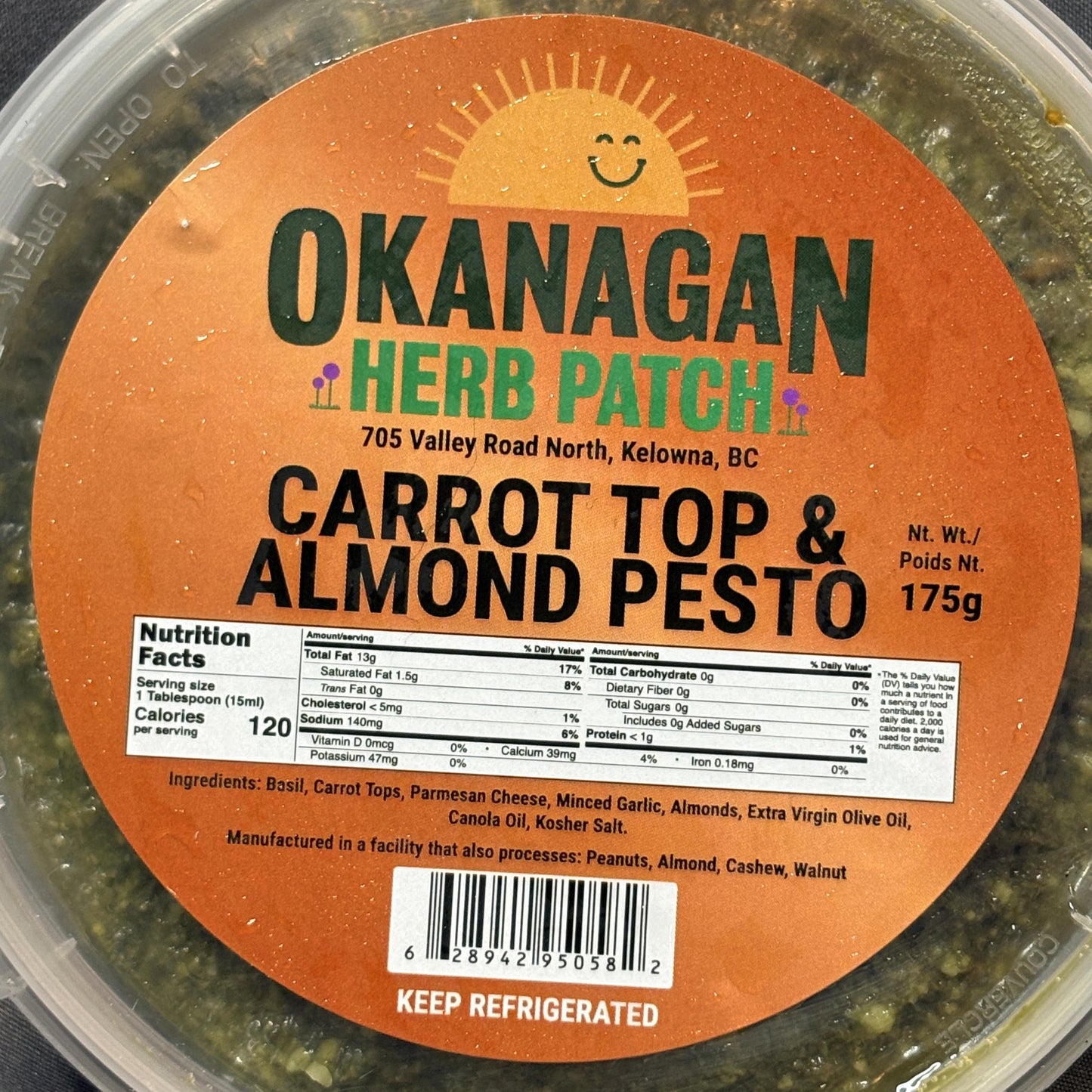 Container of Okanagan Herb Patch Carrot Top & Almond Pesto with label on a dark background
